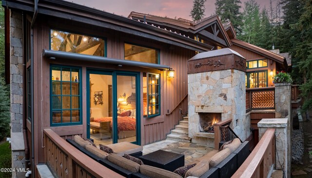 back house at dusk with a patio area and an outdoor stone fireplace