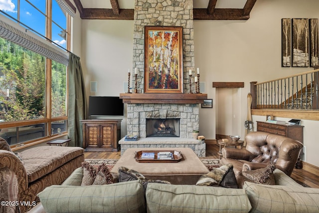 825 Forest Rd Unit 2, Vail, CO 81657 - living room featuring beam ceiling, a high ceiling, wood finished floors, a fireplace, and stairway