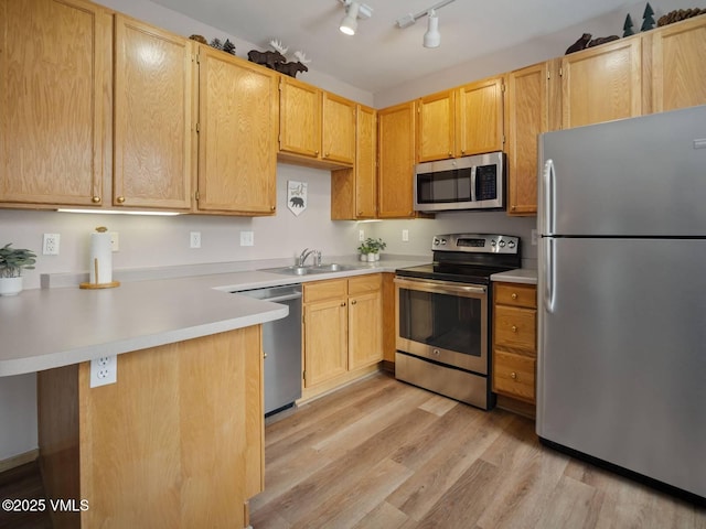 10000 Ryan Gulch Rd Unit 114, Silverthorne, CO 80498 - kitchen featuring appliances with stainless steel finishes, a peninsula, light wood finished floors, light countertops, and light brown cabinetry