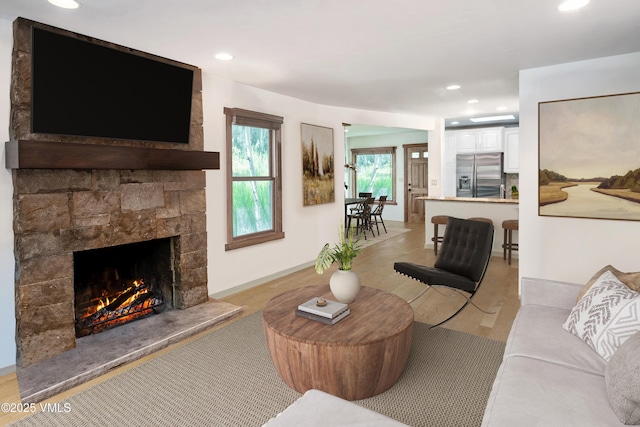 living area with recessed lighting and a stone fireplace