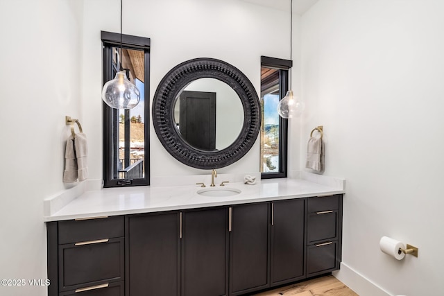 bathroom with baseboards, wood finished floors, and vanity