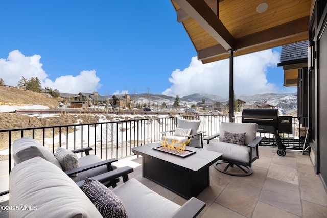 snow covered patio featuring a mountain view, an outdoor living space with a fire pit, and a balcony