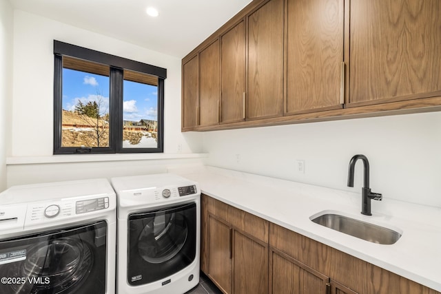 laundry room featuring washer and dryer, cabinet space, and a sink