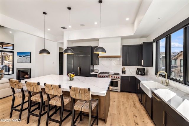 kitchen featuring visible vents, a sink, premium appliances, a kitchen island, and dark cabinetry