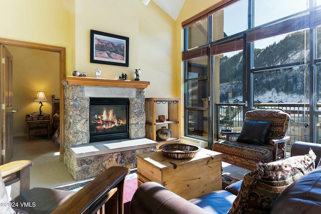 living room with carpet flooring, a stone fireplace, and high vaulted ceiling