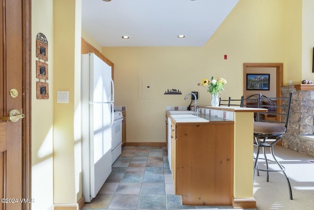 kitchen featuring sink, white appliances, a kitchen bar, tile countertops, and kitchen peninsula