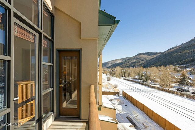 snow covered back of property with a mountain view