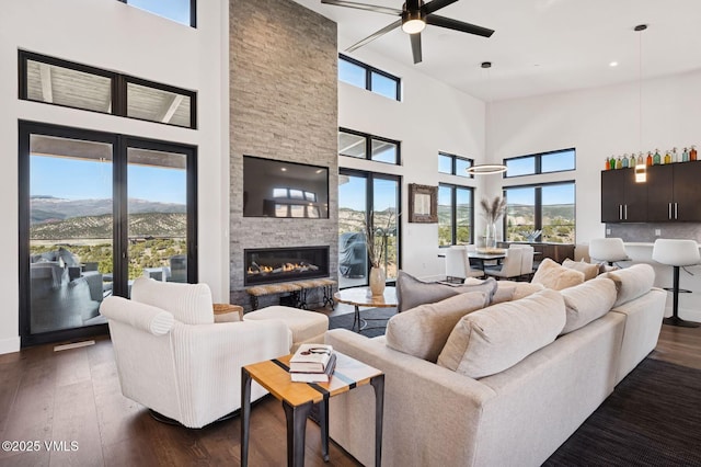 2296 E Haystacker Dr, Eagle, CO 81631 - living room featuring ceiling fan, a high ceiling, dark wood-type flooring, and a stone fireplace