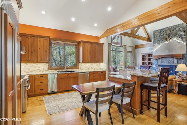 kitchen with brown cabinets, open floor plan, vaulted ceiling with beams, light stone countertops, and a sink