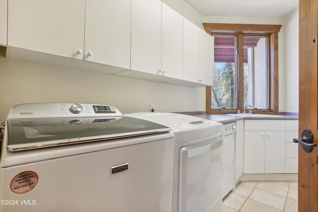 laundry room featuring cabinet space, light tile patterned flooring, a sink, and independent washer and dryer