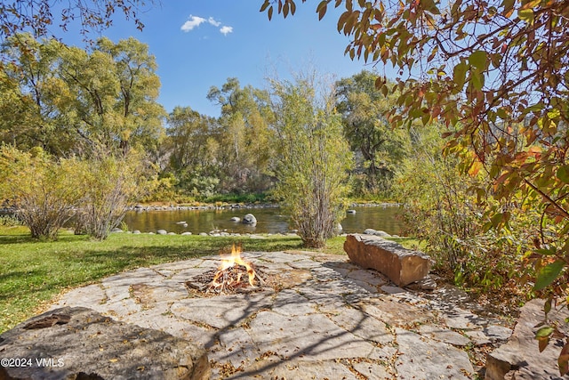 view of patio with an outdoor fire pit and a water view