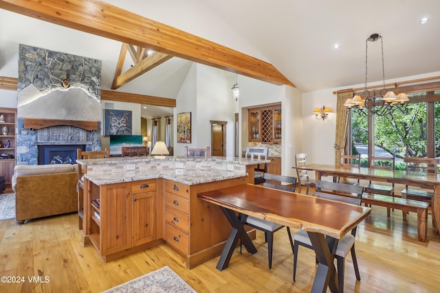 kitchen with pendant lighting, a fireplace, open floor plan, a kitchen island, and light stone countertops