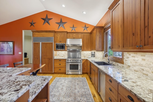 kitchen with light stone countertops, under cabinet range hood, and built in appliances