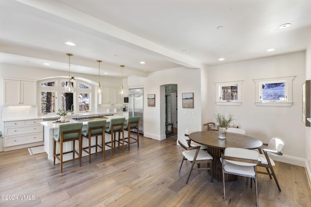 dining room with beam ceiling and light wood-type flooring