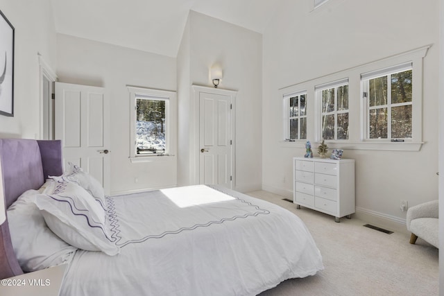 bedroom featuring light carpet and a high ceiling