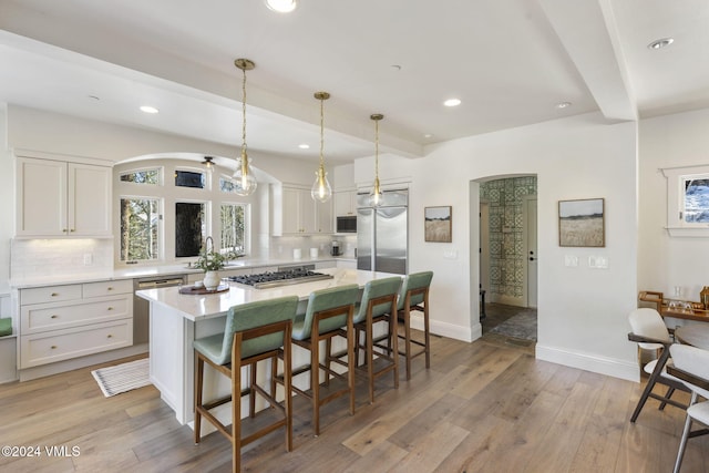 kitchen with beamed ceiling, white cabinetry, a center island, and tasteful backsplash