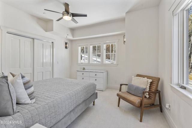 carpeted bedroom featuring multiple windows, ceiling fan, and a closet