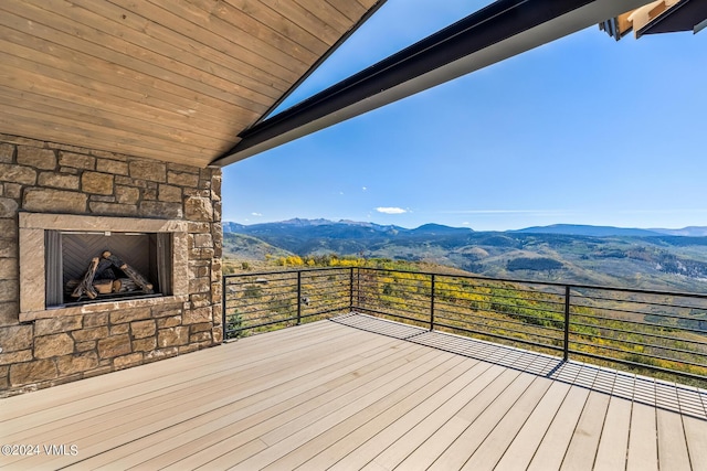 wooden deck featuring a mountain view and an outdoor stone fireplace