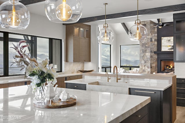 966 Webb Peak, Edwards, CO 81632 - kitchen featuring a sink, a fireplace, light stone countertops, ceiling fan, and decorative light fixtures