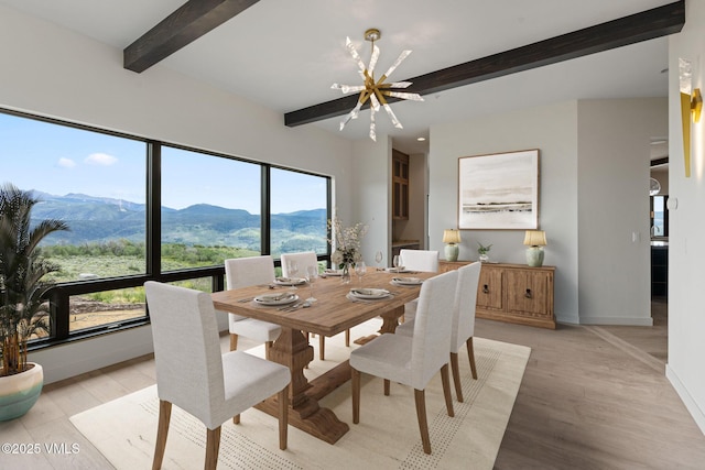 dining room featuring an inviting chandelier, beam ceiling, a mountain view, and light hardwood / wood-style floors