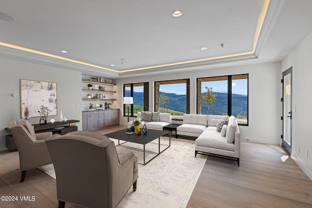 living room with a mountain view, light hardwood / wood-style floors, a raised ceiling, and indoor bar