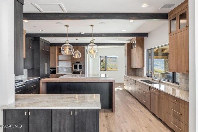 kitchen with decorative light fixtures, sink, decorative backsplash, a large island with sink, and beam ceiling