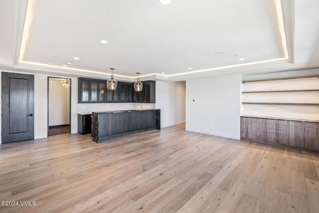 kitchen with dark brown cabinetry, a center island, light hardwood / wood-style floors, and a tray ceiling