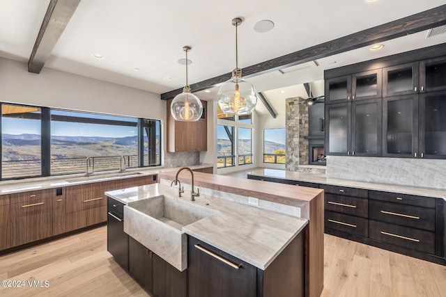 kitchen featuring sink, a center island with sink, light hardwood / wood-style flooring, a mountain view, and pendant lighting