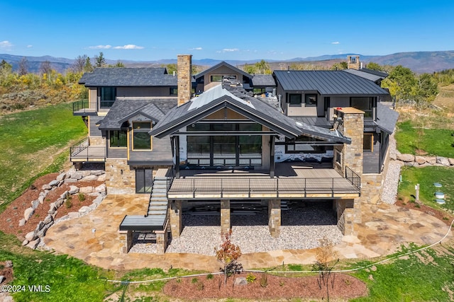 rear view of property with a patio, a mountain view, and a balcony