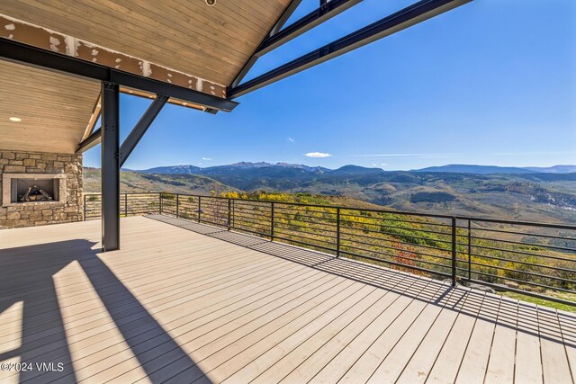 deck featuring a mountain view and an outdoor stone fireplace