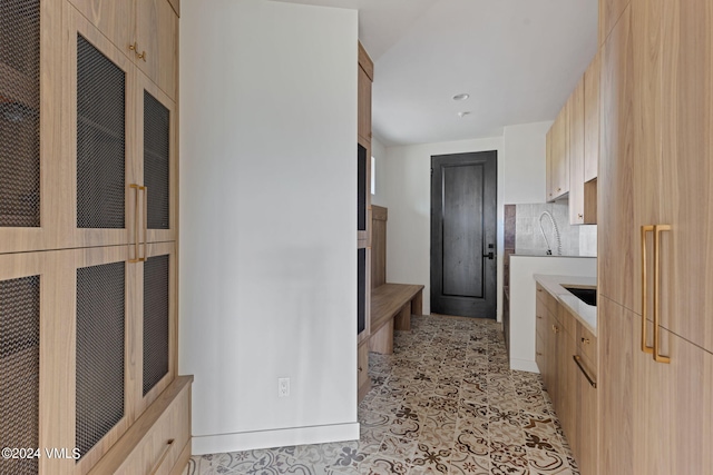 kitchen with tasteful backsplash, light brown cabinetry, and sink