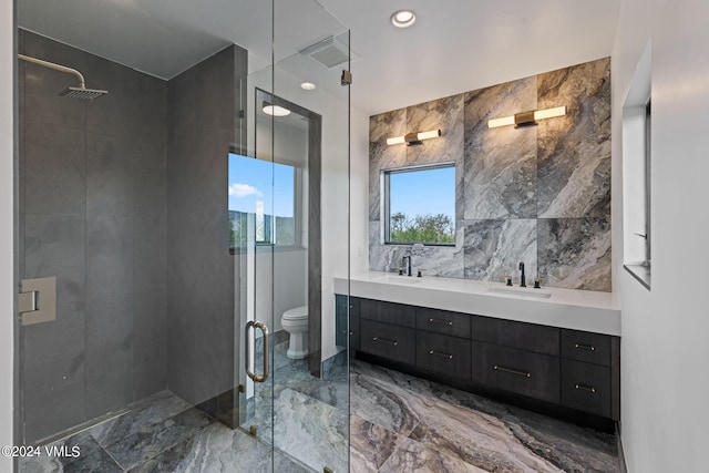 bathroom with vanity, toilet, a shower with door, and tile walls