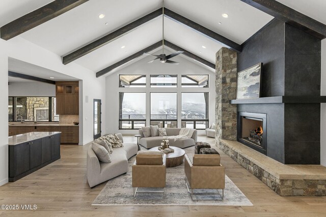 966 Webb Peak, Edwards, CO 81632 - living room featuring beamed ceiling, a stone fireplace, light wood finished floors, high vaulted ceiling, and a ceiling fan