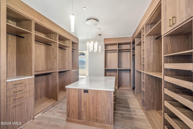 spacious closet featuring an inviting chandelier and light hardwood / wood-style floors