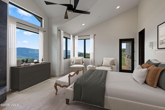 bedroom featuring multiple windows, a mountain view, access to outside, and light hardwood / wood-style floors