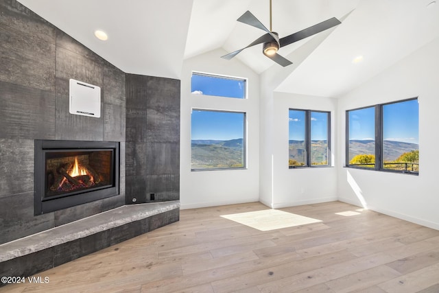 unfurnished living room with a mountain view, a wealth of natural light, light hardwood / wood-style flooring, and a fireplace