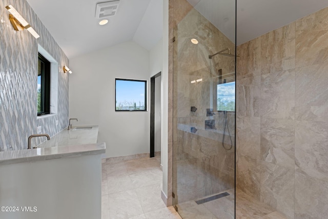 bathroom with a healthy amount of sunlight, lofted ceiling, tiled shower, and tile patterned floors