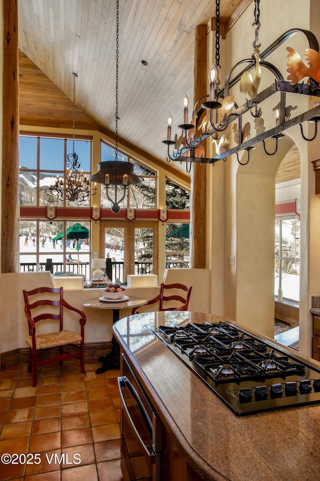 kitchen with tile patterned flooring, wood ceiling, black gas stovetop, arched walkways, and a notable chandelier