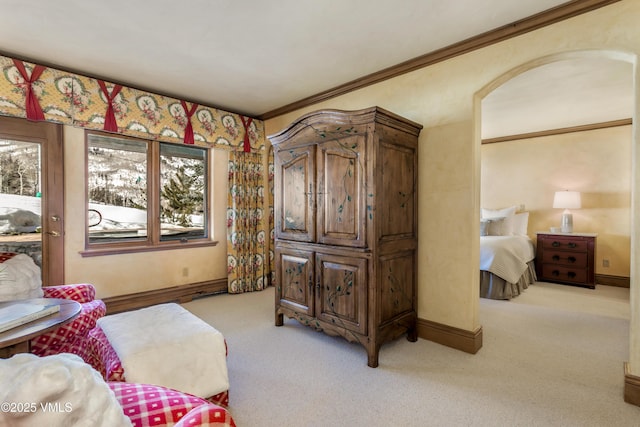 living area with crown molding, arched walkways, baseboards, and light carpet