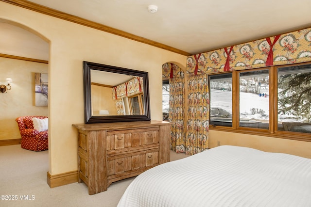 bedroom featuring baseboards, light carpet, arched walkways, and crown molding