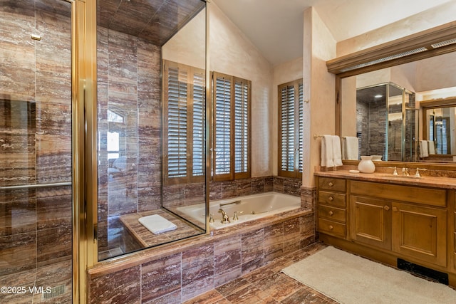 full bath with a tub with jets, vanity, and vaulted ceiling