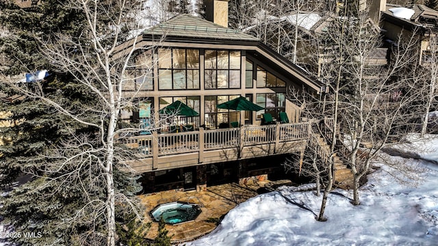 rear view of house featuring an in ground hot tub and a chimney