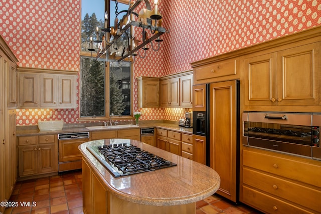 kitchen featuring a sink, a center island, paneled appliances, wallpapered walls, and light tile patterned floors