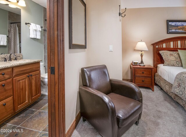 bedroom with sink, dark carpet, and ensuite bath