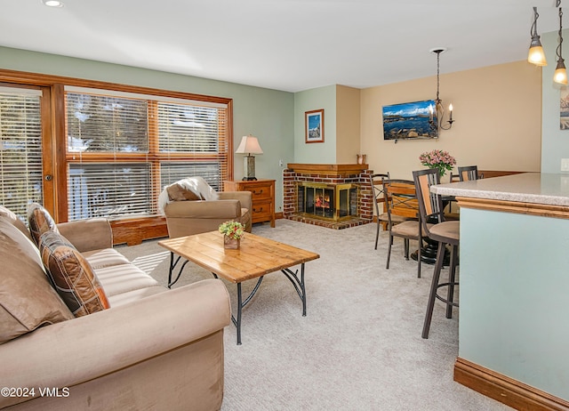 living room featuring light colored carpet, a brick fireplace, and a notable chandelier