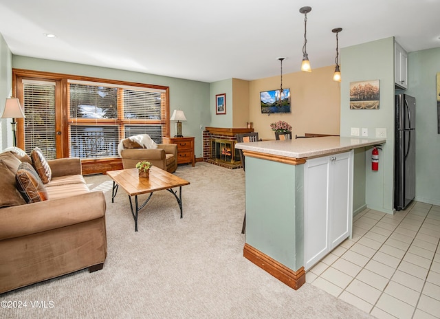 kitchen featuring decorative light fixtures, stainless steel fridge, white cabinets, light colored carpet, and kitchen peninsula