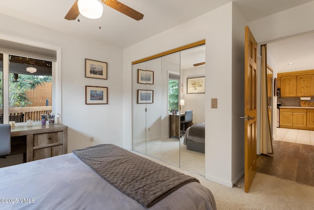 bedroom with a closet, a ceiling fan, light colored carpet, and baseboards