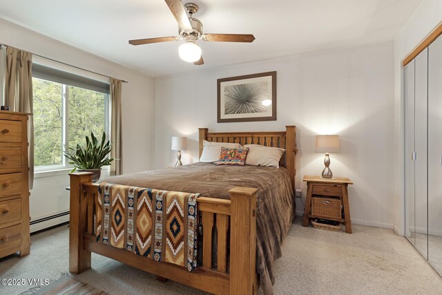 bedroom featuring a baseboard heating unit, light carpet, a closet, and a ceiling fan
