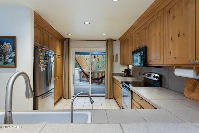 kitchen with stainless steel appliances, tile countertops, recessed lighting, light tile patterned floors, and backsplash