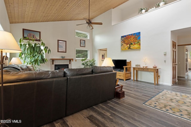 living area featuring a ceiling fan, a tiled fireplace, dark wood-type flooring, high vaulted ceiling, and baseboards